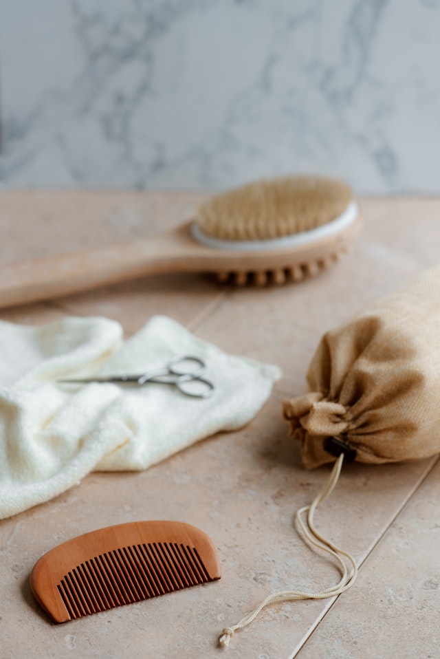 bamboo comb next to bath brush, towel, scissors and linen bag