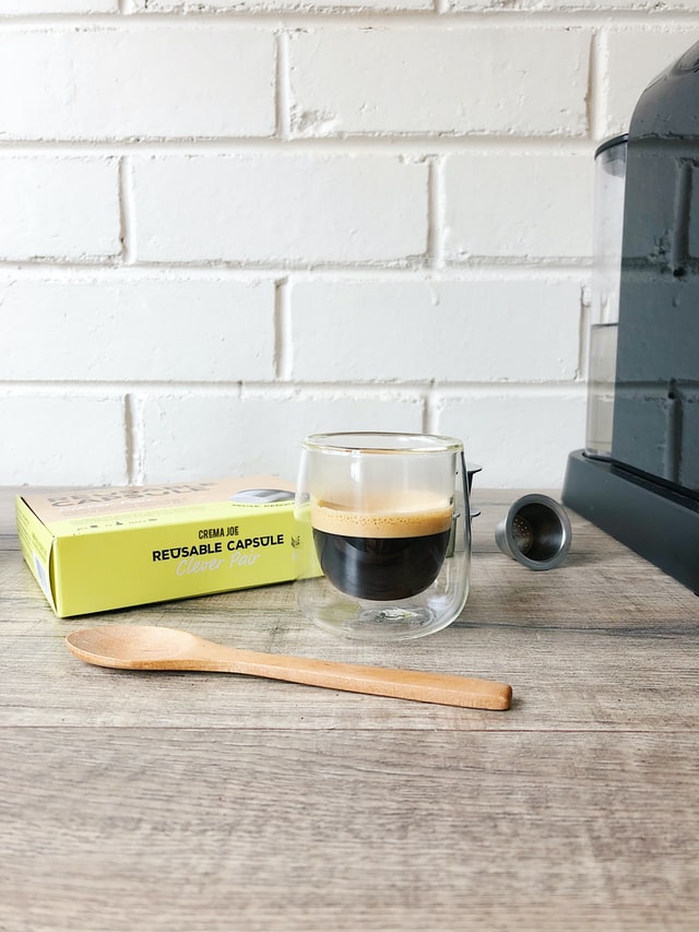 reusable coffee pod with cup of coffee and bamboo spoon on countertop