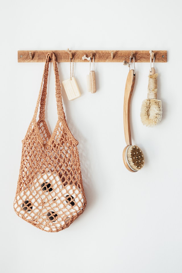 sustainable bathroom items hanging on hooks including toilet paper, soap and two bath brushes