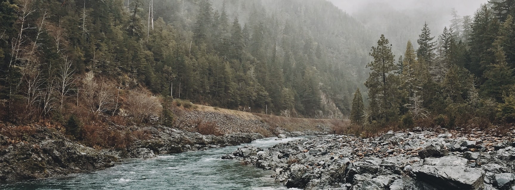 photograph of nature landscape with mountains, trees, rocks and water