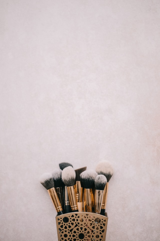 make brushes in gold container with pink and gray background color