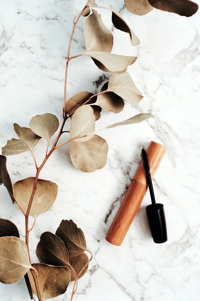 bamboo mascara container on white marble with eucalyptus