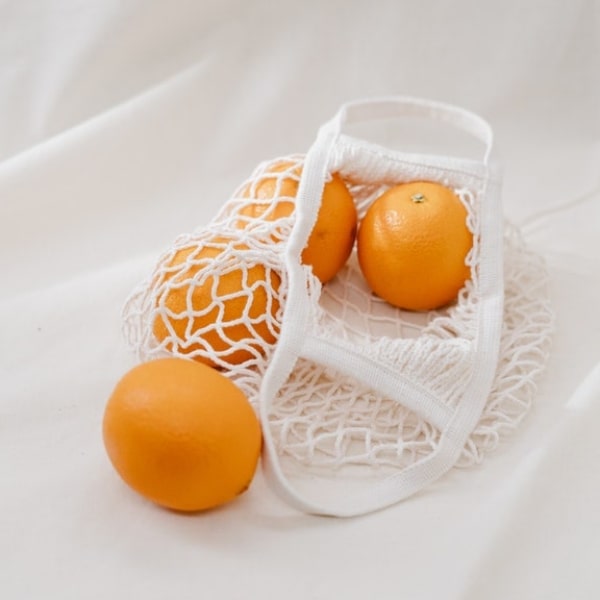 reusable produce bag with four oranges inside of it