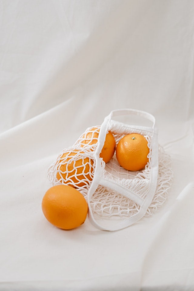 reusable produce bag with four oranges inside of it