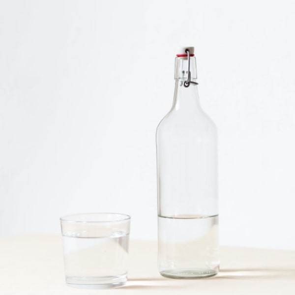 glass bottle and glass cup half full